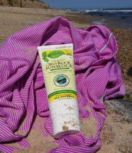 Surfer applying 3rd Rock SunBlock with white tint before entering the ocean